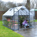 Gardener working inside an 8 x 12 Balance greenhouse with shelving and plants