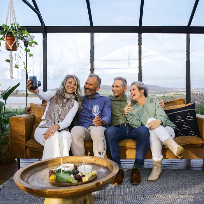 Family enjoying time inside Triomphe garden chalet greenhouse with seating and decor