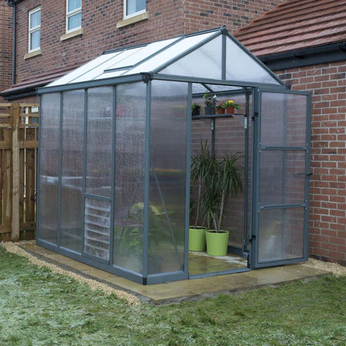 Glory 6x8 greenhouse installed in a backyard with brick wall and paved base