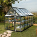 6x10 hybrid greenhouse positioned in a garden setting with surrounding lawn and plants