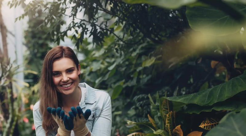 A smiling woman wearing gardening gloves.